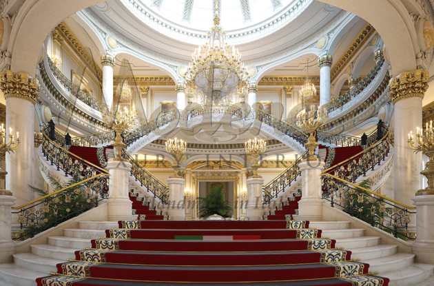 Palace entry with stairs red carpet on the steps columns and chandelier Modenese interior design